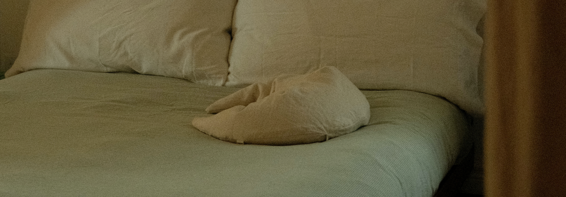 a beige and crescent shaped nursing pillow on a bed